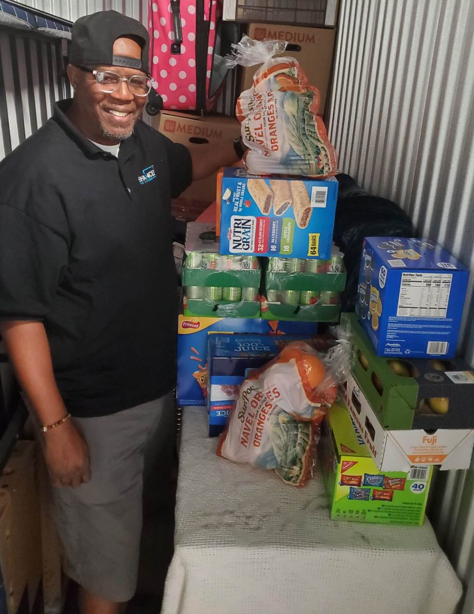 A volunteer standing beside shelves of donated food and supplies