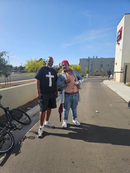A volunteer posing with a neighbor on a sunny sidewalk