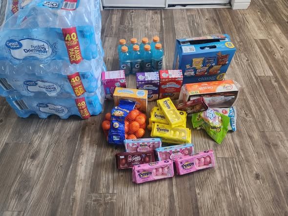 A close-up of cases of water, sports drinks, oranges, and snack boxes